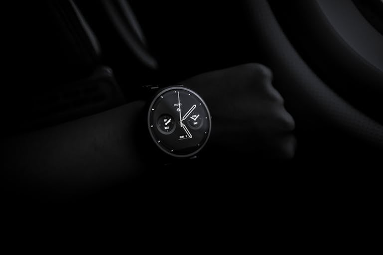 Sotwe A sleek Moto 360 smartwatch showing time on a wrist in a dimly lit setting, emphasizing its modern design and technology.