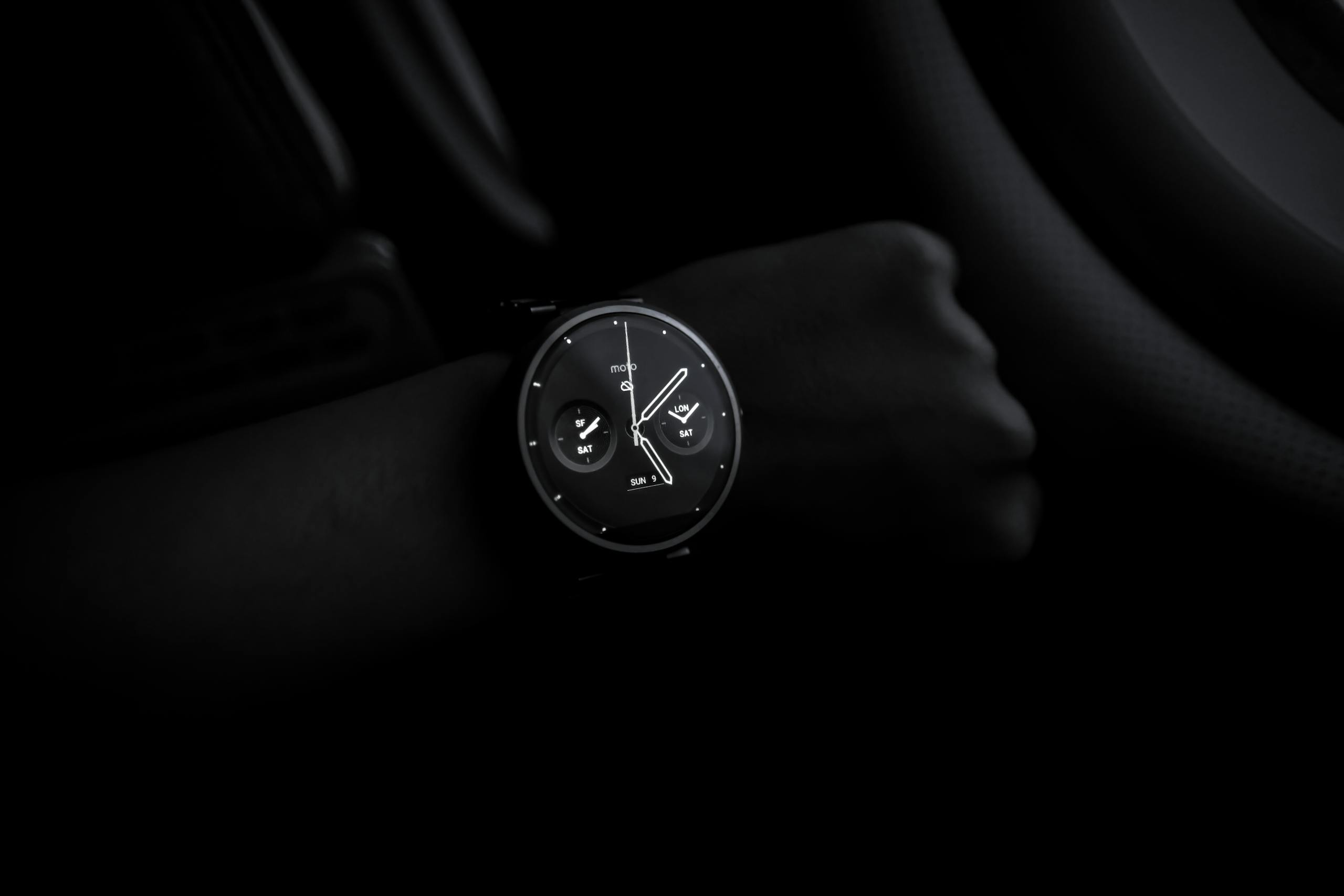 Sotwe A sleek Moto 360 smartwatch showing time on a wrist in a dimly lit setting, emphasizing its modern design and technology.