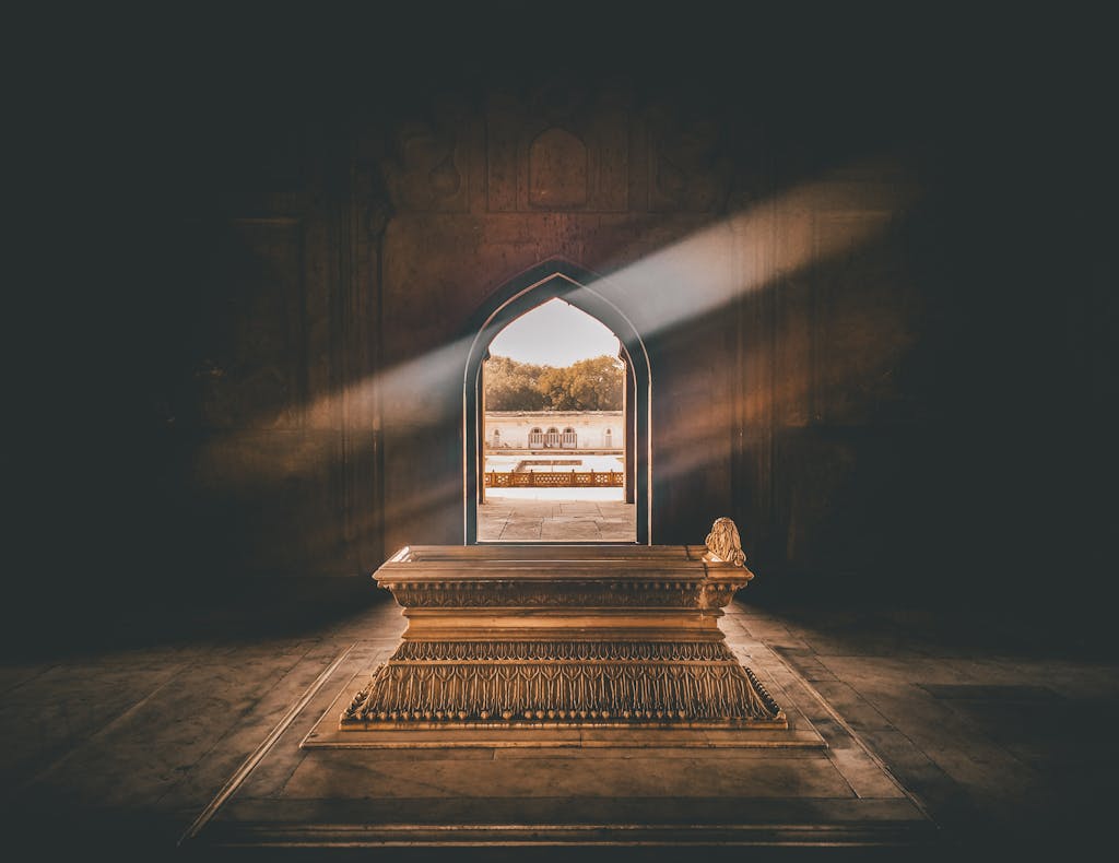ksözcü Beautiful tomb interior with a golden sarcophagus, illuminated by sunlight through an ornate archway.