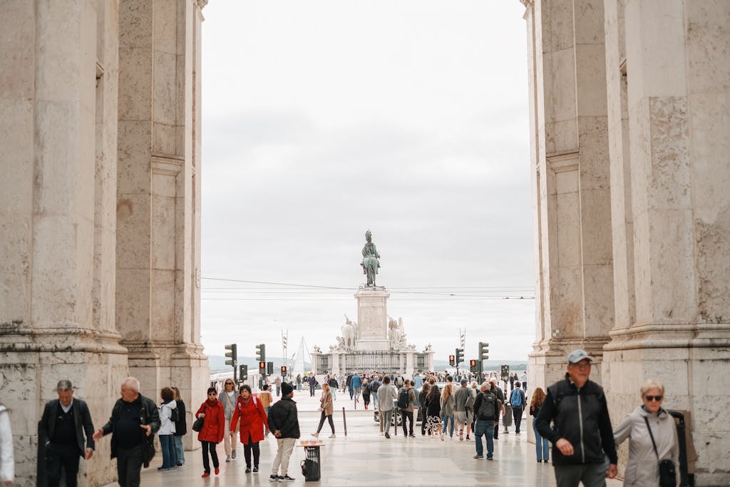 i Square  Crowd of people walking through archway towards Praça do Comércio in Lisbon.