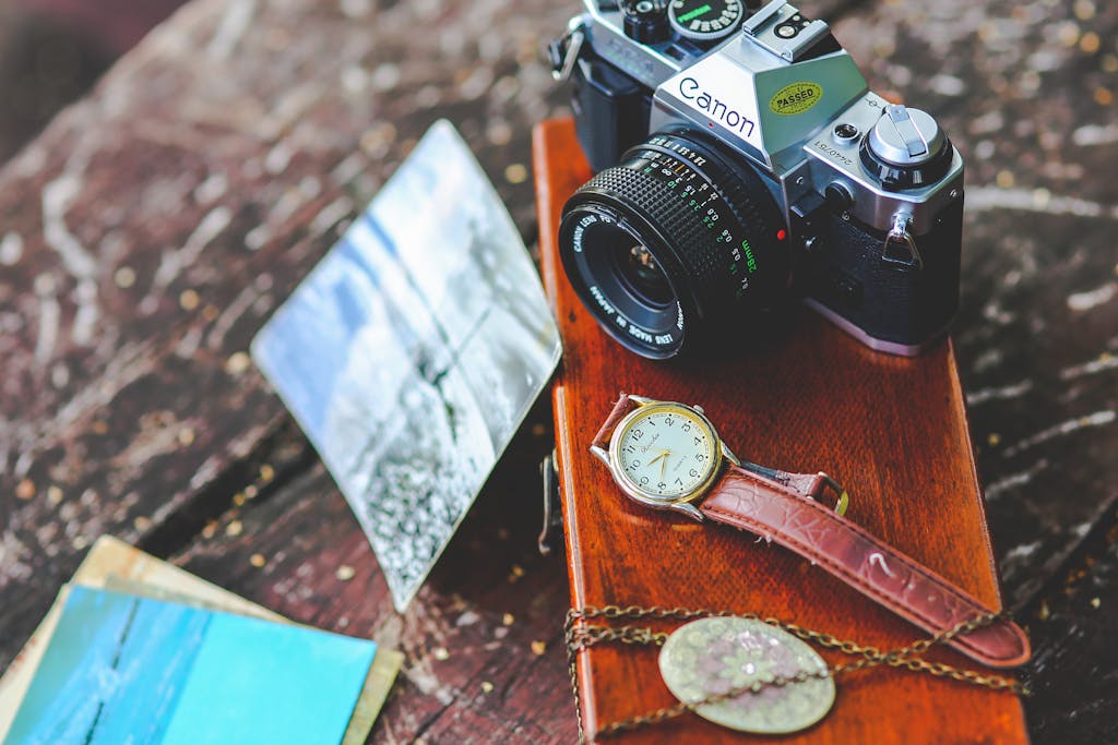 Pappedeckel Elegant composition of a vintage camera, watch, and photos on a rustic wooden table.