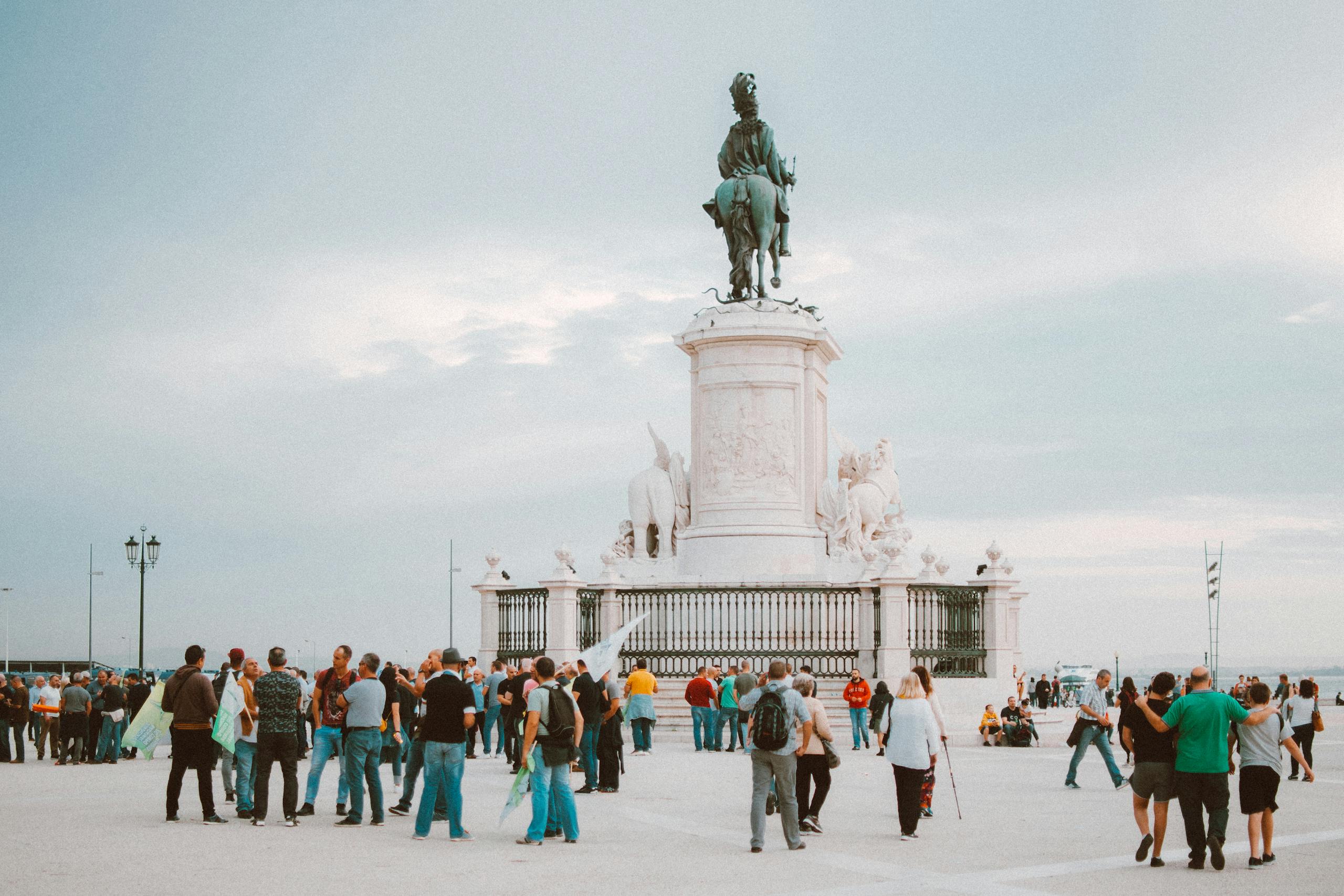 i Square Tourists gather around the iconic statue in Lisbon, Portugal, enjoying a sunny day.
