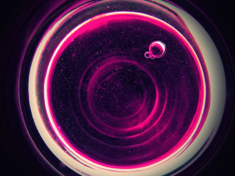 Bastinews.xyz Vibrant abstract pink bubbles forming a circular pattern against a dark background, creating a cosmic feel.
