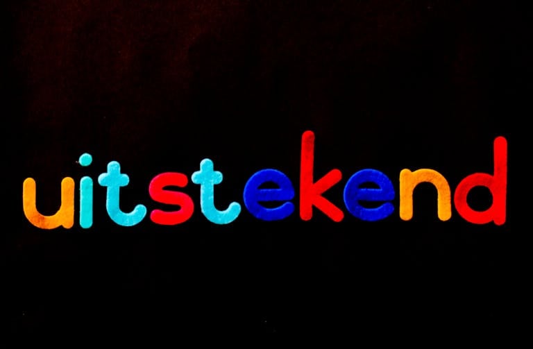 XSON208 Vibrant 'uitstekend' lettering with colorful design on a black background.