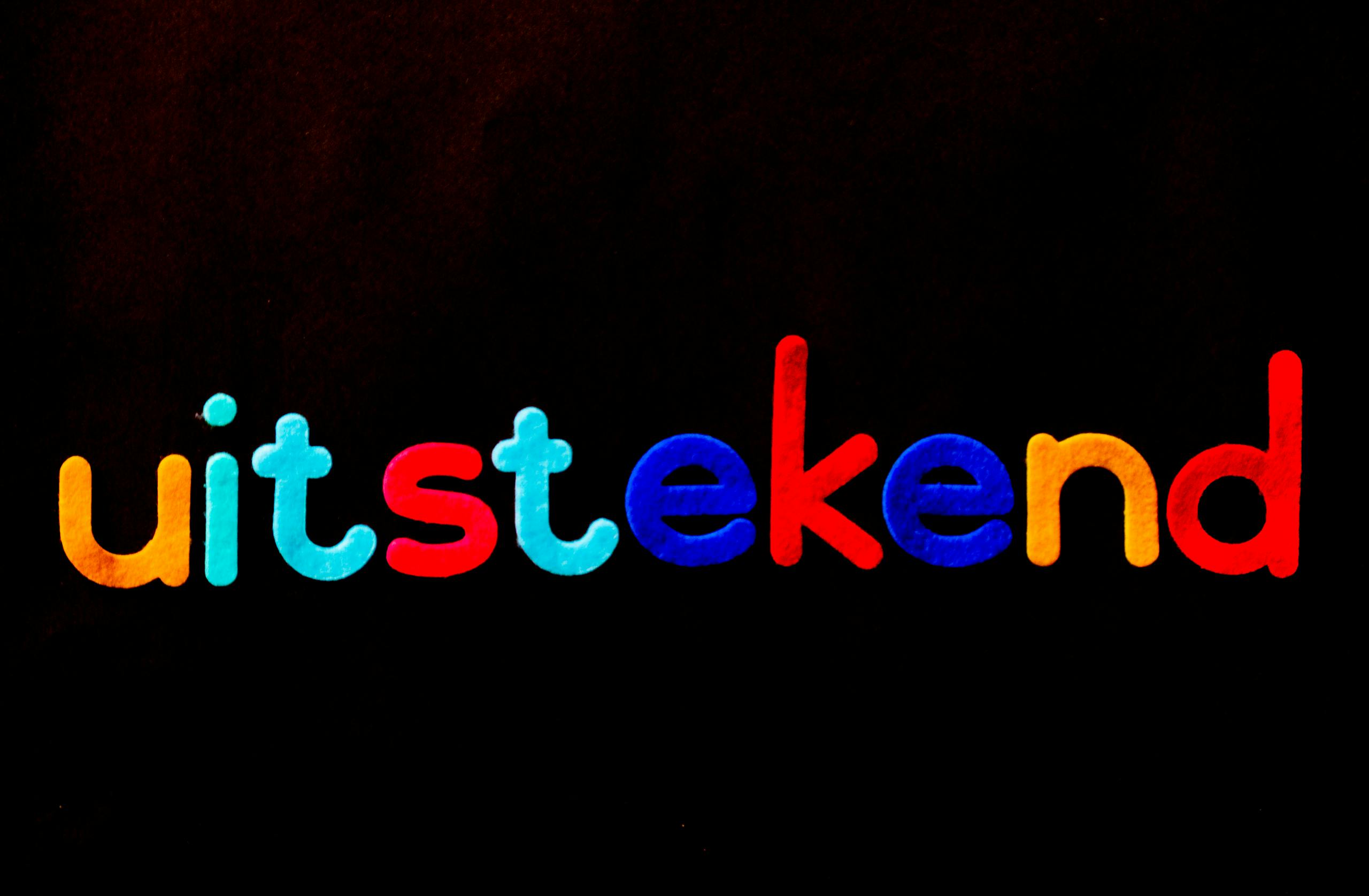 XSON208 Vibrant 'uitstekend' lettering with colorful design on a black background.