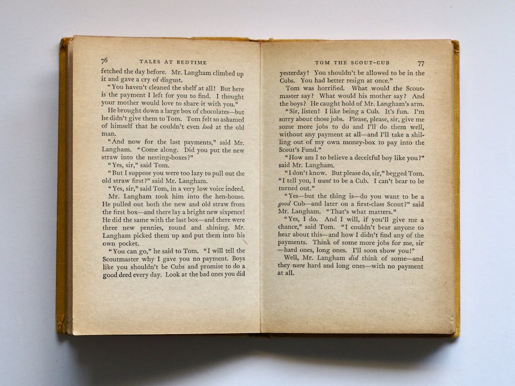Bastinews.xyz Vintage book opened to pages 76-77, displaying classic literature text in soft lighting.