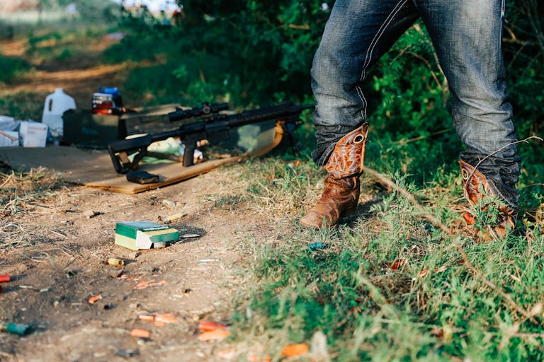 Texas Hunting Forum A person wearing cowboy boots stands outdoors, rifle on the ground surrounded by ammunition.