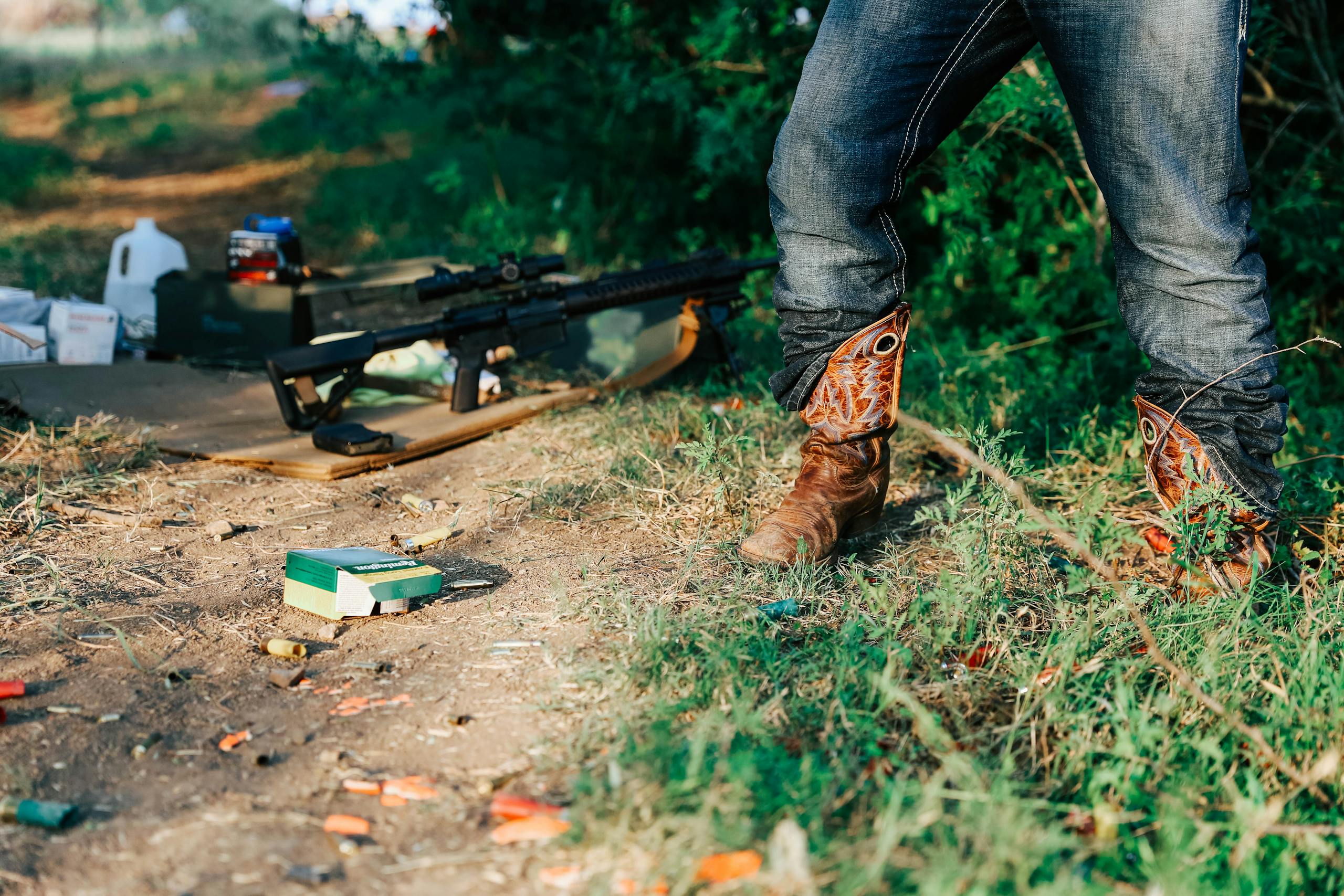 Texas Hunting Forum A person wearing cowboy boots stands outdoors, rifle on the ground surrounded by ammunition.