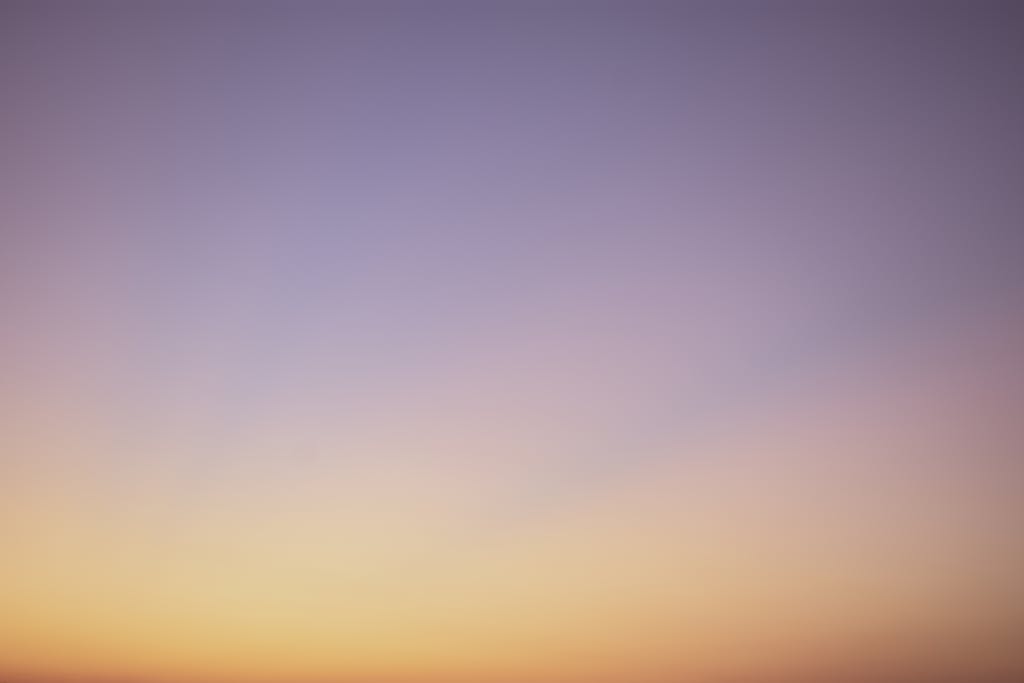Voozon A serene gradient sky with hues of blue, pink, and orange during twilight.