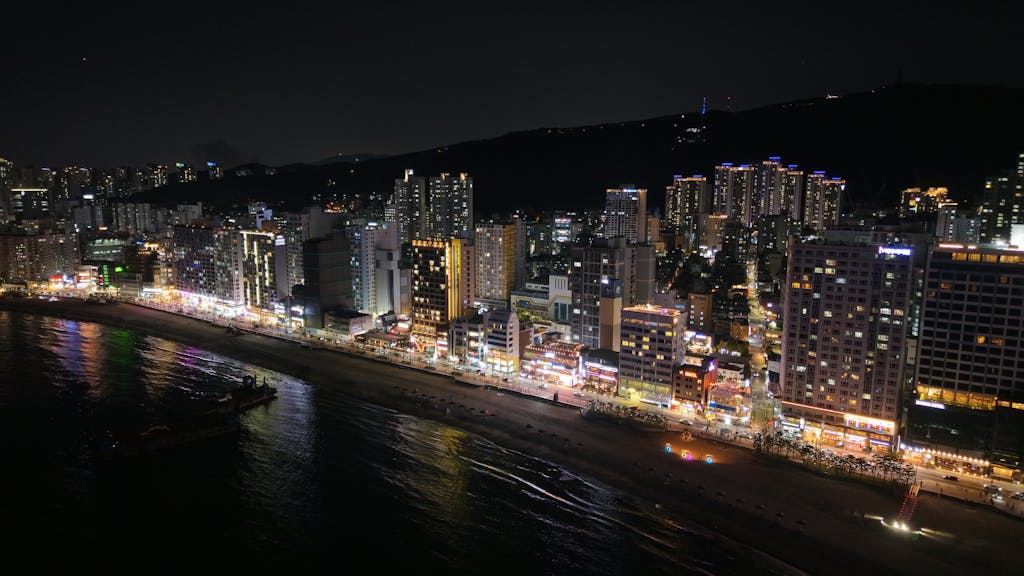 The Rise of the SocialMediaGirl A stunning nighttime view of Busan's illuminated skyline and coastline in South Korea.