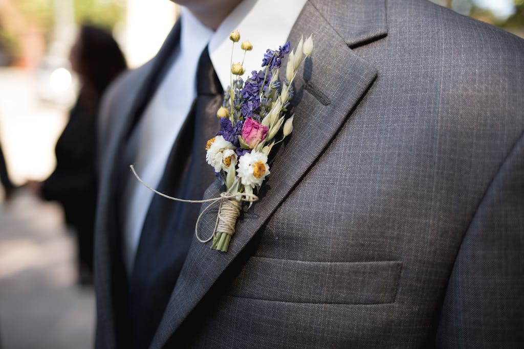 Blazertje  Close-up of an elegant groom wearing a designer suit and floral boutonniere during a wedding ceremony.