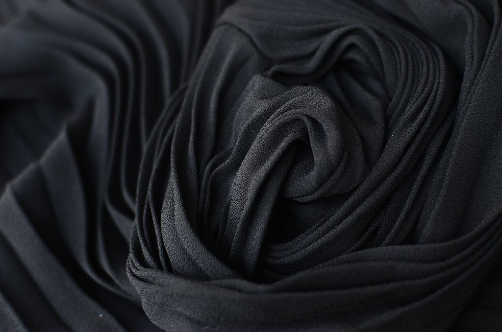 HerbCiepScam Close-up of black pleated fabric with soft, smooth texture and creative design.