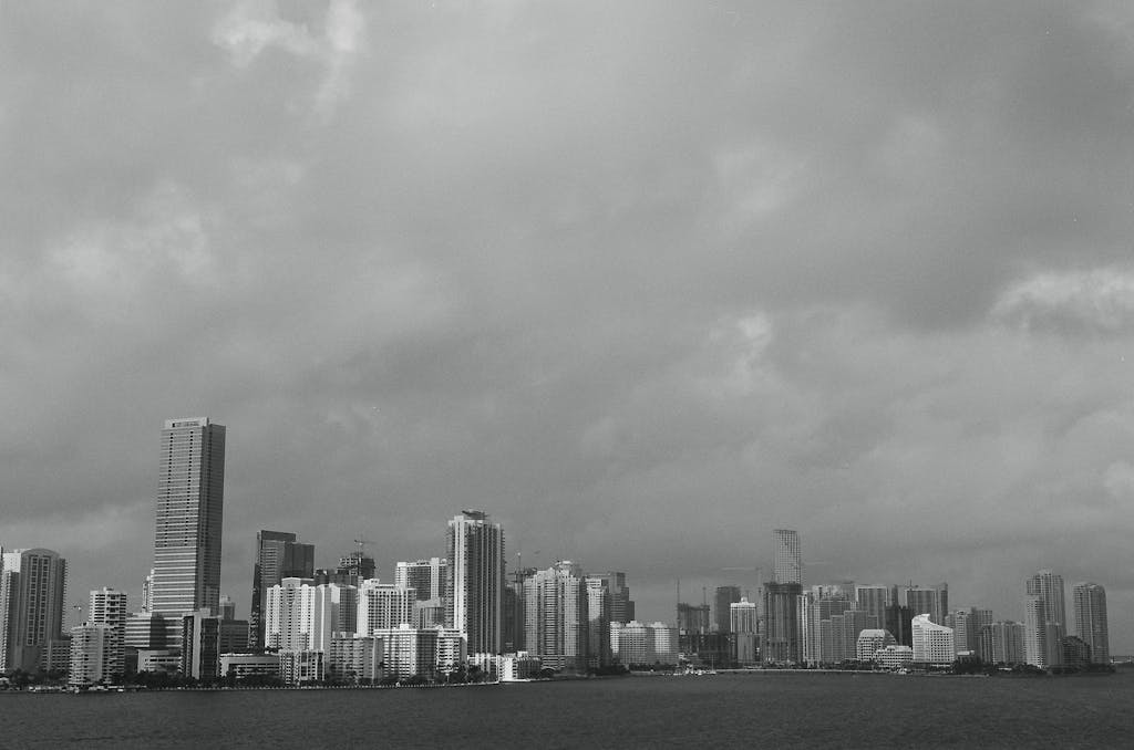 Sotwe Dramatic black and white photo of the Miami skyline under cloudy skies, capturing urban architecture.