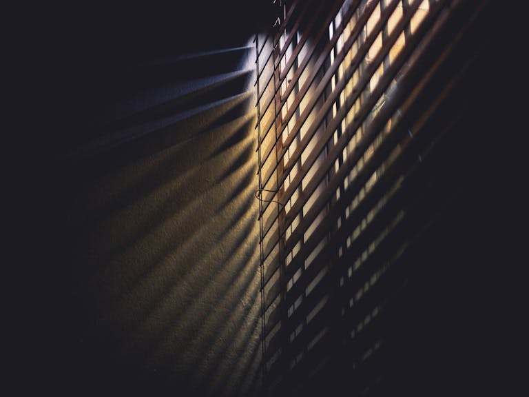 Sotwe Dramatic light and shadows cast through window blinds, creating a moody atmosphere.