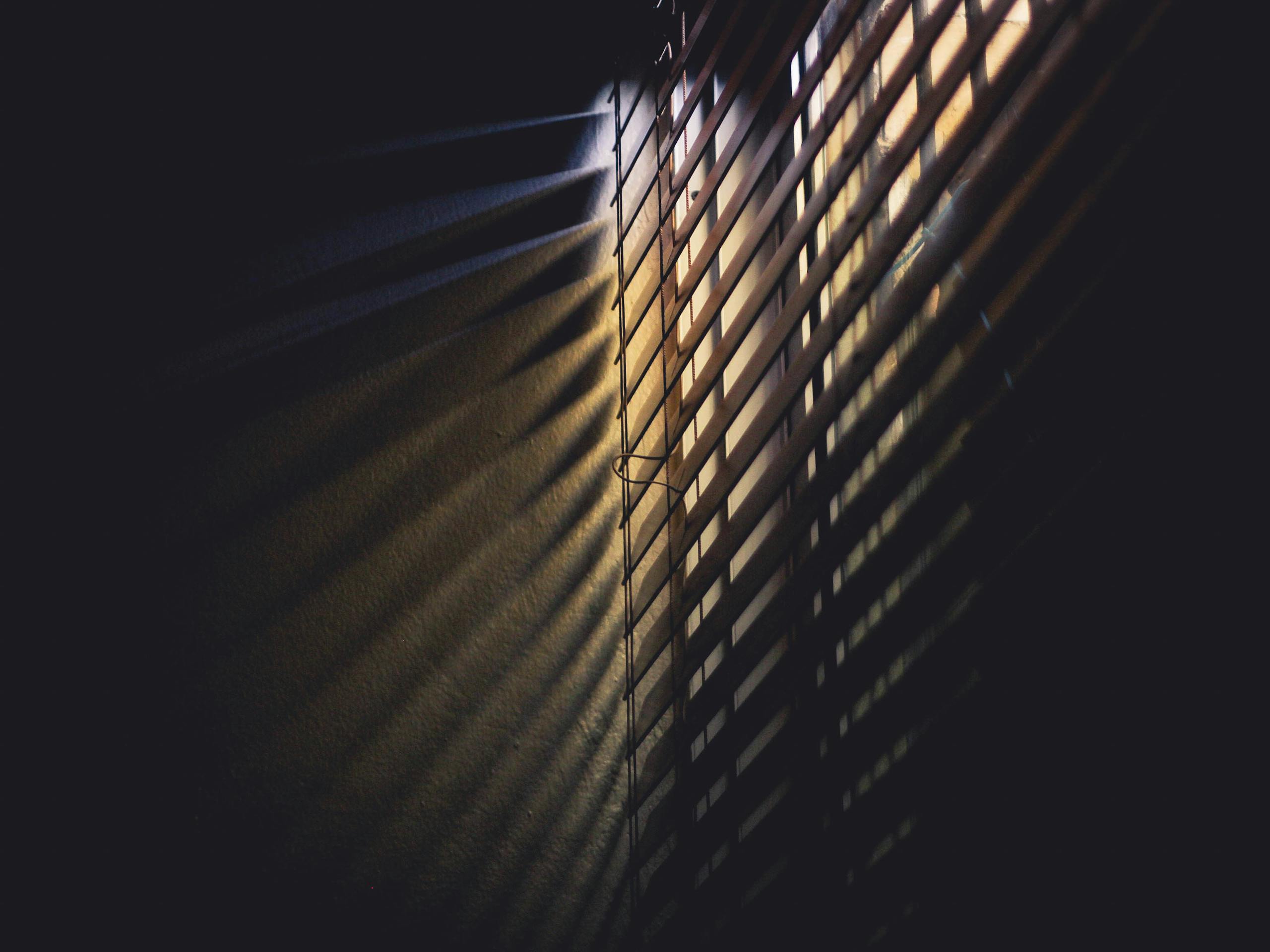 Sotwe Dramatic light and shadows cast through window blinds, creating a moody atmosphere.