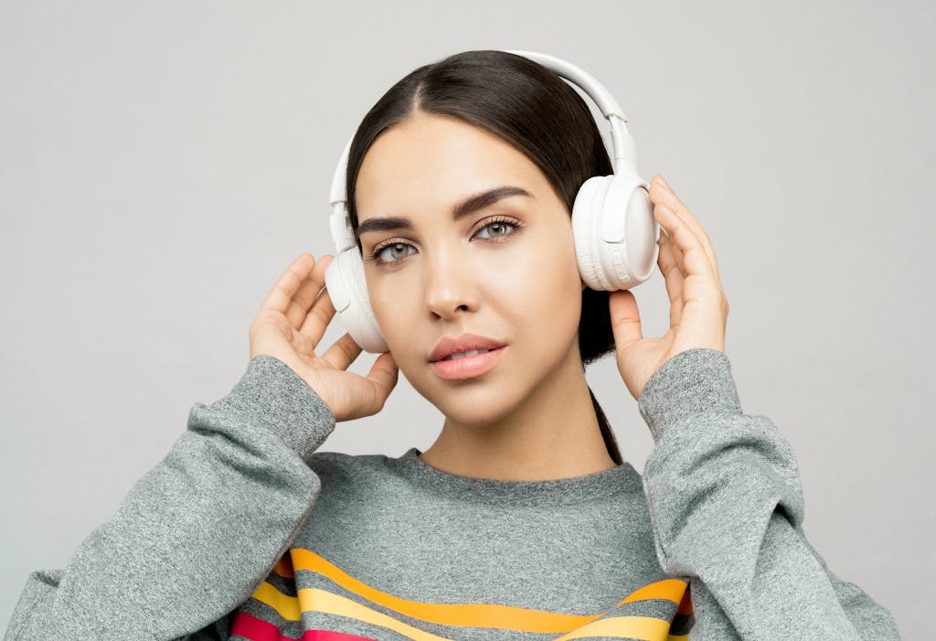 Beautiful Portrait of a young woman wearing headphones, enjoying music indoors with a casual expression.