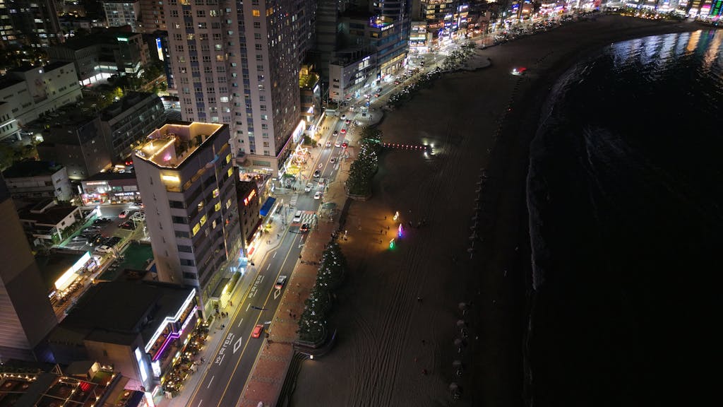 The Rise of the SocialMediaGirl Stunning aerial night view of Haeundae Beach, Busan, showcasing vibrant city lights along the coastline.