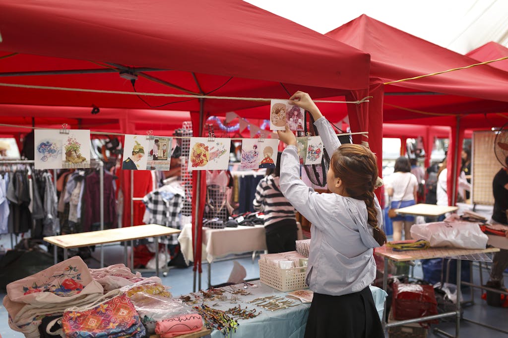 Messeregge Vibrant marketplace with red tents, shoppers, and colorful goods on display.