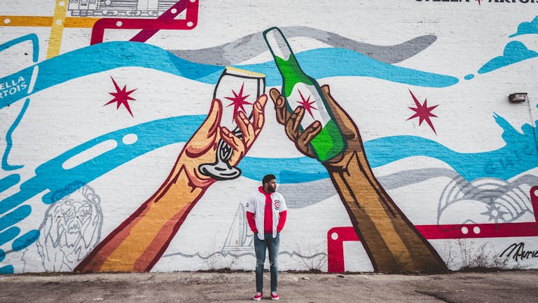 Chicago Cubs Vibrant street art in Chicago depicting hands holding drinks, observed by a young adult.