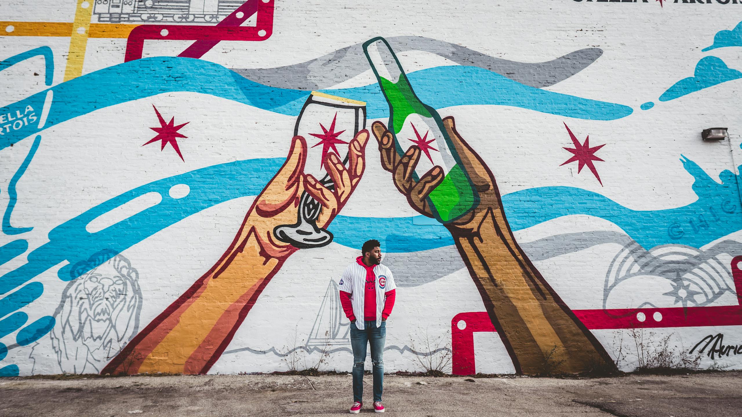 Chicago Cubs Vibrant street art in Chicago depicting hands holding drinks, observed by a young adult.