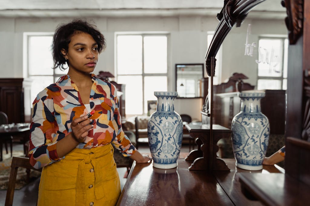 Shop Spring Vase Woman in a colorful shirt admiring her reflection in a mirror with vases, in an antique shop setting.