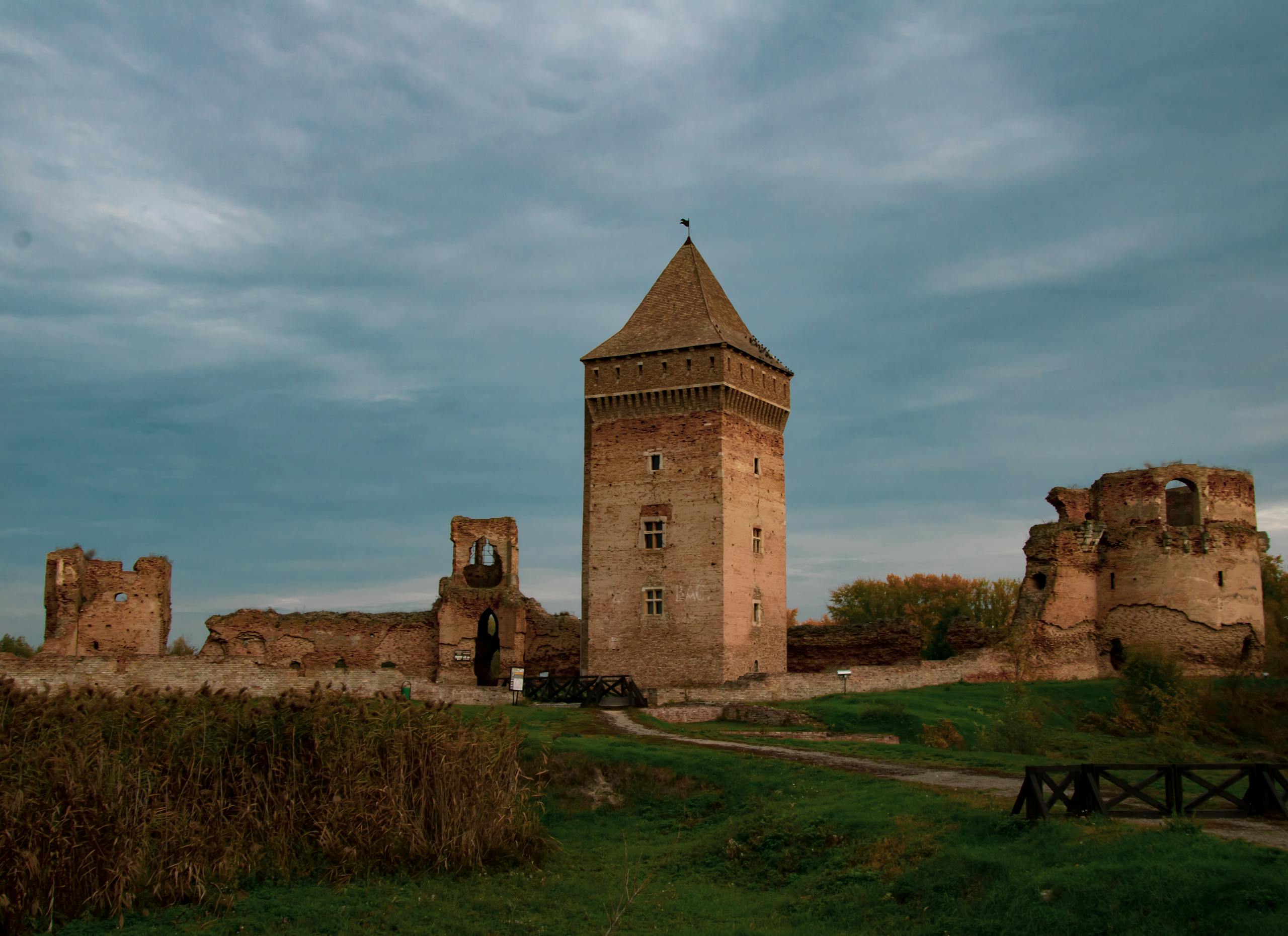 bac stock Historic medieval tower and ruins in Bač, Serbia, captured under a cloudy sky.